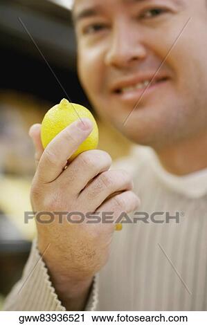Portrait of a mid adult man holding a lemon and smiling View Large Photo Image Stock Image - Portrait of a mid adult man holding a lemon and smiling. Fotosearch