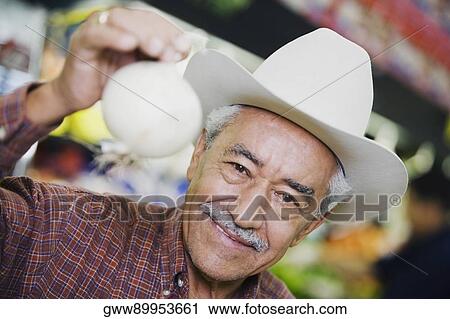 Stock Image - Portrait of a senior man holding an onion. Fotosearch