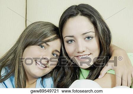 Stock Image - Portrait of a teenage girl sitting with her sister and smiling. Fotosearch