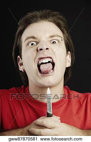 Portrait of a young man holding a knife up to his chin and sticking his tongue out View Large Photo Image Stock Image - Portrait of a young man holding a knife up to his chin and sticking his tongue out. Fotosearch