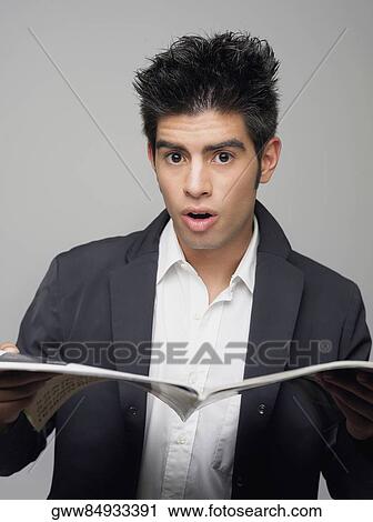 Stock Image - Portrait of a young man holding a magazine. Fotosearch