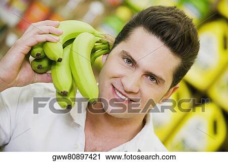 Portrait of a young man holding bananas View Large Photo Image Stock Image - Portrait of a young man holding bananas. Fotosearch