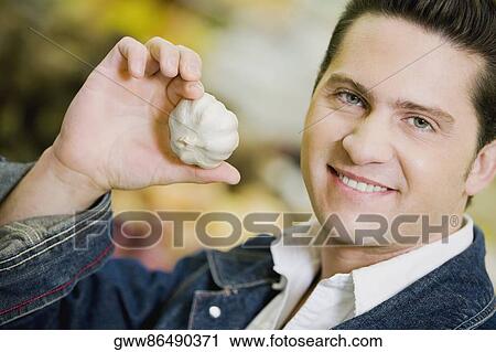 Portrait of a young man holding garlic View Large Photo Image Stock Image - Portrait of a young man holding garlic. Fotosearch
