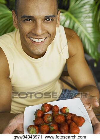 Portrait of a young man offering a plate of strawberries View Large Photo Image Stock Image - Portrait of a young man offering a plate of strawberries. Fotosearch