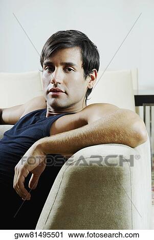 Portrait of a young man sitting on a couch View Large Photo Image Stock Image - Portrait of a young man sitting on a couch. Fotosearch