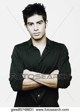 Portrait of a young man standing with his arms crossed View Large Photo Image Stock Image - Portrait of a young man standing with his arms crossed. Fotosearch