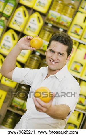 Portrait of a young man throwing an orange in a supermarket View Large Photo Image Stock Image - Portrait of a young man throwing an orange in a supermarket. Fotosearch