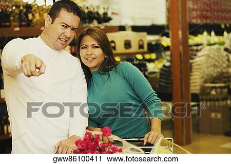 Portrait of a young woman and a mid adult man standing in a supermarket View Large Photo Image Stock Image - Portrait of a young woman and a mid adult man standing in a supermarket. Fotosearch