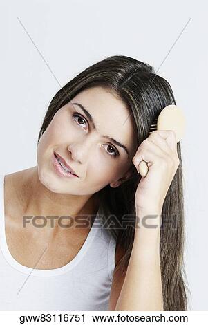 Stock Image - Portrait of a young woman combing her hair. Fotosearch