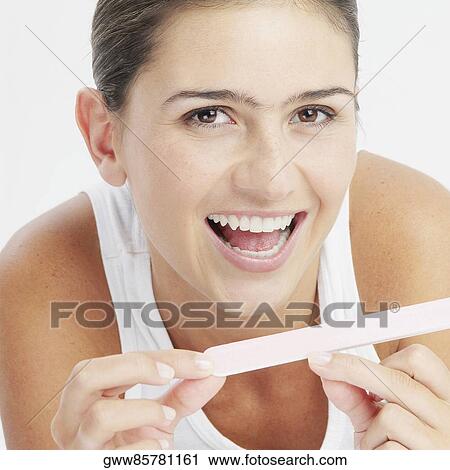 Portrait of a young woman filing her nails and smiling View Large Photo Image Stock Image - Portrait of a young woman filing her nails and smiling. Fotosearch