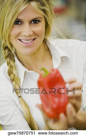 Portrait of a young woman holding a red bell pepper View Large Photo Image Stock Image - Portrait of a young woman holding a red bell pepper. Fotosearch