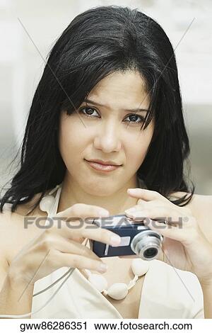 Stock Image - Portrait of a young woman holding a digital camera. Fotosearch