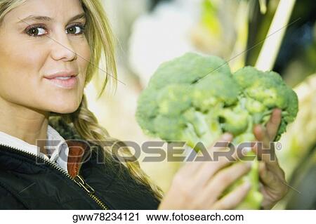 Portrait of a young woman holding broccoli View Large Photo Image Stock Image - Portrait of a young woman holding broccoli. Fotosearch