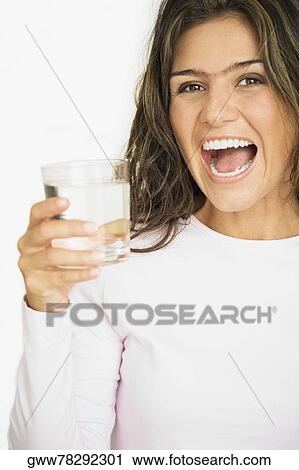 Portrait of a young woman laughing and holding a glass of water View Large Photo Image Stock Image - Portrait of a young woman laughing and holding a glass of water. Fotosearch