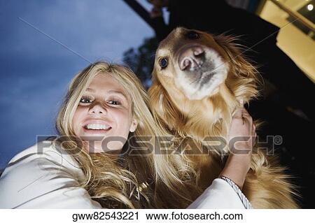 Stock Image - Portrait of a young woman smiling with her dog. Fotosearch