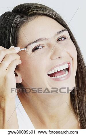 Portrait of a young woman tweezing her eyebrow and laughing View Large Photo Image Stock Image - Portrait of a young woman tweezing her eyebrow and laughing. Fotosearch