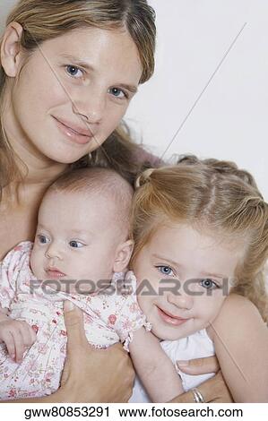 Stock Image - Portrait of a young woman with her two baby girls. Fotosearch