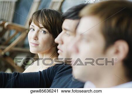 Stock Image - Portrait of a young woman with two young men. Fotosearch