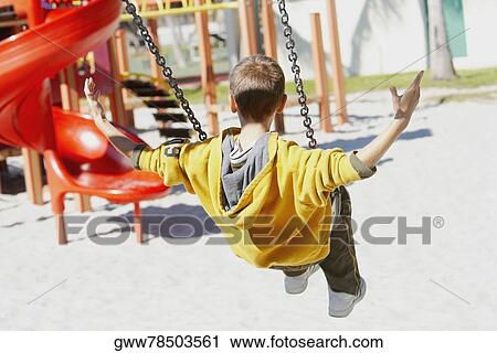 Rear view of a boy swinging on a chain swing ride with his arm outstretched View Large Photo Image Stock Image - Rear view of a boy swinging on a chain swing ride with his arm outstretched. Fotosearch