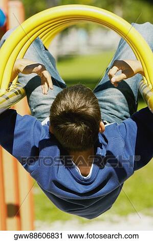 Rear view of a teenage boy hanging upside down on a jungle gym View Large Photo Image Stock Image - Rear view of a teenage boy hanging upside down on a jungle gym. Fotosearch