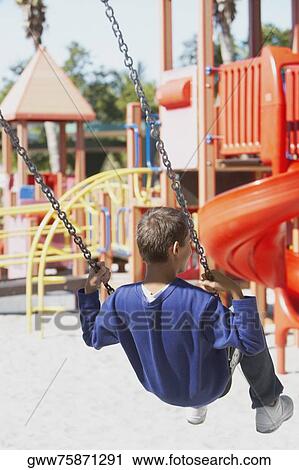 Rear view of a teenage boy swinging on a chain swing ride View Large Photo Image Stock Image - Rear view of a teenage boy swinging on a chain swing ride. Fotosearch