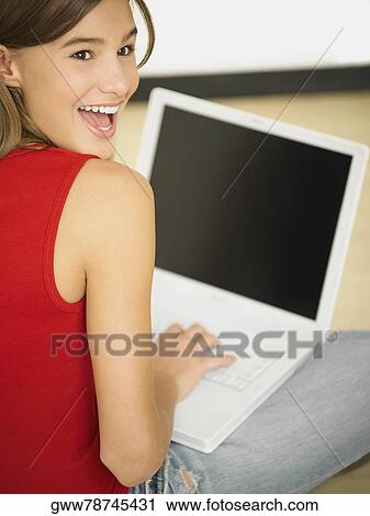 Stock Image - Rear view of a young woman using a laptop. Fotosearch