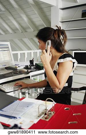 Side profile of a businesswoman using a mobile phone and working on a desktop PC View Large Photo Image Stock Image - Side profile of a businesswoman using a mobile phone and working on a desktop PC. Fotosearch