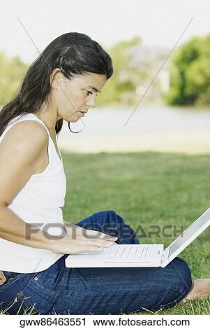 Side profile of a mid adult woman sitting in a park and using a laptop View Large Photo Image Stock Image - Side profile of a mid adult woman sitting in a park and using a laptop. Fotosearch