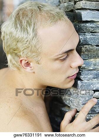 Side profile of a young man leaning against a wall View Large Photo Image Stock Image - Side profile of a young man leaning against a wall. Fotosearch