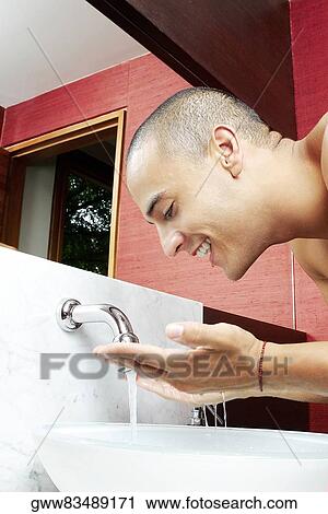 Side profile of a young man washing his face in the bathroom sink View Large Photo Image Stock Image - Side profile of a young man washing his face in the bathroom sink. Fotosearch