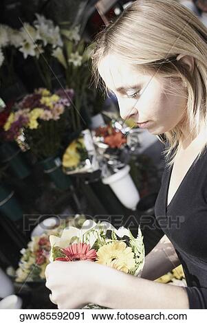 Side profile of a young woman holding a bouquet of flowers View Large Photo Image Stock Image - Side profile of a young woman holding a bouquet of flowers. Fotosearch