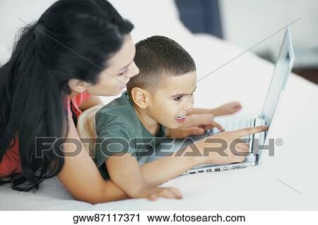 Side profile of a young woman teaching his son to use a laptop View Large Photo Image Stock Image - Side profile of a young woman teaching his son to use a laptop. Fotosearch