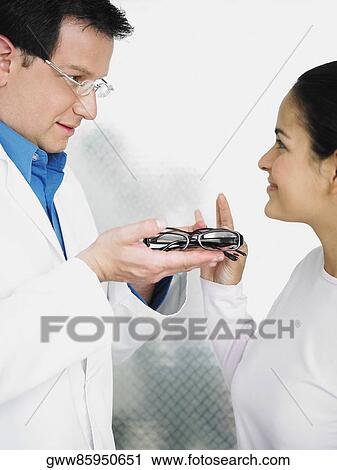 Side profile of male doctor giving eyeglasses to a female patient View Large Photo Image Stock Image - Side profile of male doctor giving eyeglasses to a female patient. Fotosearch