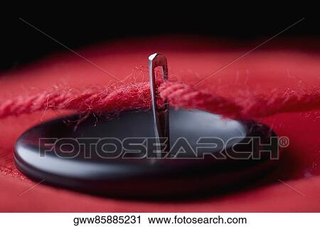 Strand of wool through the eye of a needle with a button View Large Photo Image Stock Image - Strand of wool through the eye of a needle with a button. Fotosearch