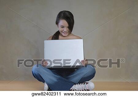 Teenage girl sitting on the floor with a laptop on her lap View Large Photo Image Stock Image - Teenage girl sitting on the floor with a laptop on her lap. Fotosearch