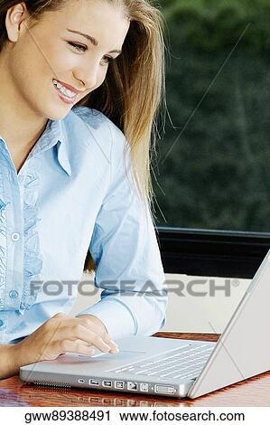 Stock Image - Teenage girl using a laptop and smiling. Fotosearch