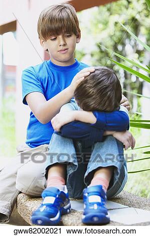 Two boys sitting on a ledge View Large Photo Image Stock Image - Two boys sitting on a ledge. Fotosearch