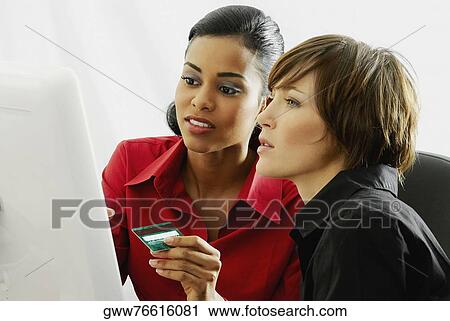 Two businesswomen looking at a computer monitor View Large Photo Image Stock Image - Two businesswomen looking at a computer monitor. Fotosearch