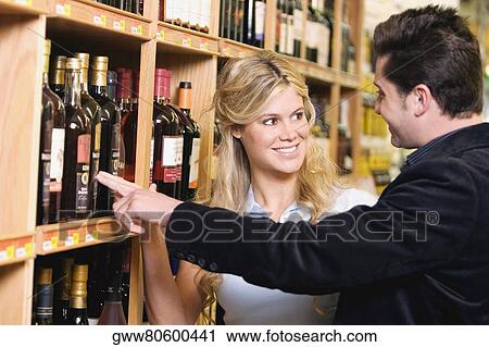 Young couple choosing wine in a liquor store View Large Photo Image Stock Image - Young couple choosing wine in a liquor store. Fotosearch