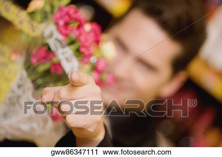 Young man holding a bouquet of flowers and pointing View Large Photo Image Stock Image - Young man holding a bouquet of flowers and pointing. Fotosearch