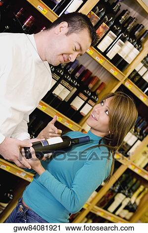 Young woman and a mid adult man in wine shop View Large Photo Image Stock Image - Young woman and a mid adult man in wine shop. Fotosearch