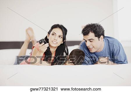 Young woman and a mid adult man lying down with their son on the bed View Large Photo Image Stock Image - Young woman and a mid adult man lying down with their son on the bed. Fotosearch