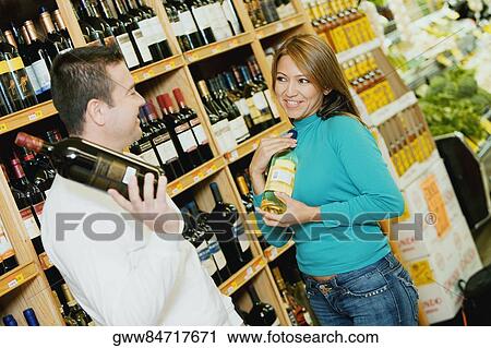 Young woman and a mid adult man choosing wine in a wine shop View Large Photo Image Stock Image - Young woman and a mid adult man choosing wine in a wine shop. Fotosearch