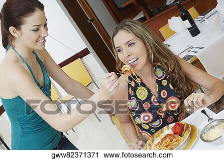 Young woman feeding another noodles View Large Photo Image Stock Image - Young woman feeding another noodles. Fotosearch
