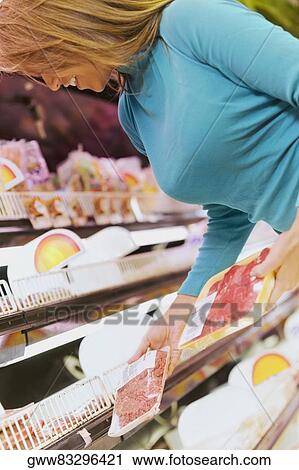 Young woman holding packets in a supermarket View Large Photo Image Stock Image - Young woman holding packets in a supermarket. Fotosearch