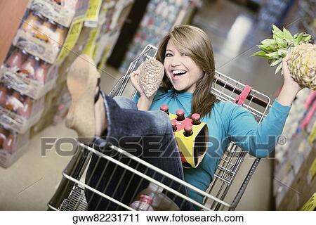Young woman sitting in a shopping cart and laughing View Large Photo Image Stock Image - Young woman sitting in a shopping cart and laughing. Fotosearch