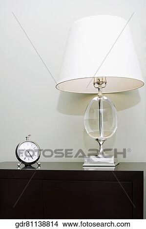 Alarm clock and a lamp on a chest View Large Photo Image Picture - Alarm clock and a lamp on a chest. Fotosearch