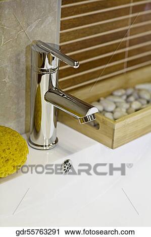Stock Image - Bath sponge near a faucet on a wash bowl. Fotosearch