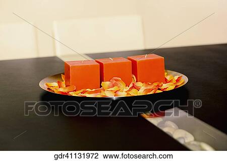 Stock Image - Candles and rose petals in a plate on a table. Fotosearch