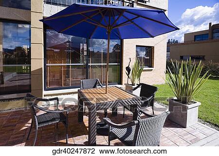 Chairs with a patio umbrella in the courtyard of a house View Large Photo Image Stock Image - Chairs with a patio umbrella in the courtyard of a house. Fotosearch